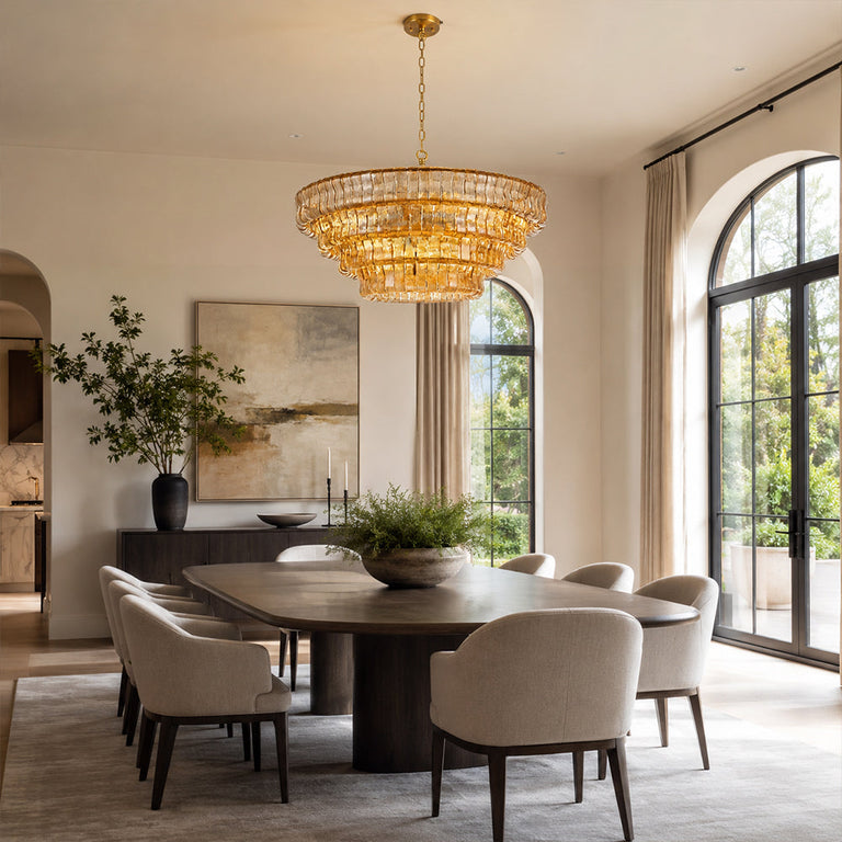 Amber round chandelier above a table by arched windows.