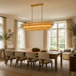 Amber glass rectangular chandelier above a sunlit dining table.