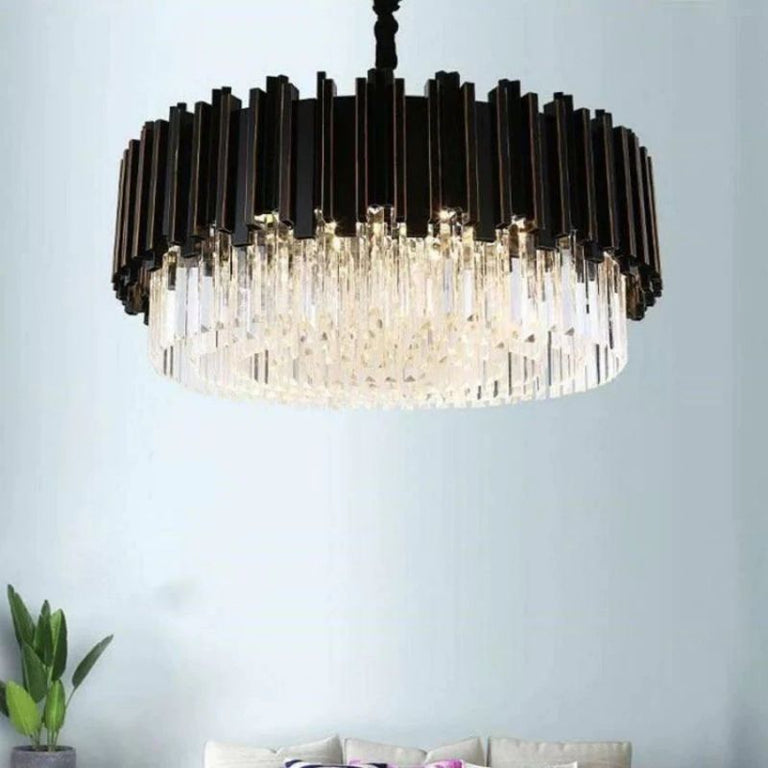 Black fin and crystal chandelier in a furnished interior beside a green plant.