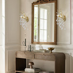 Brass crystal wall sconces beside a mirror above a console