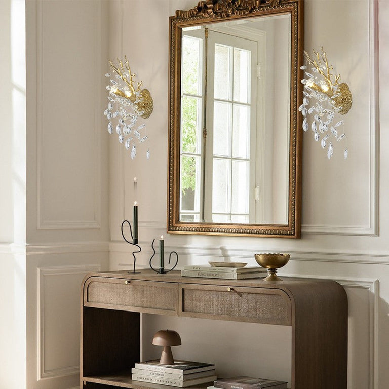 Brass crystal wall sconces beside a mirror above a console