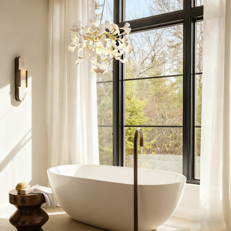 Gold-tone ceramic leaf round chandelier beside a bathroom window.