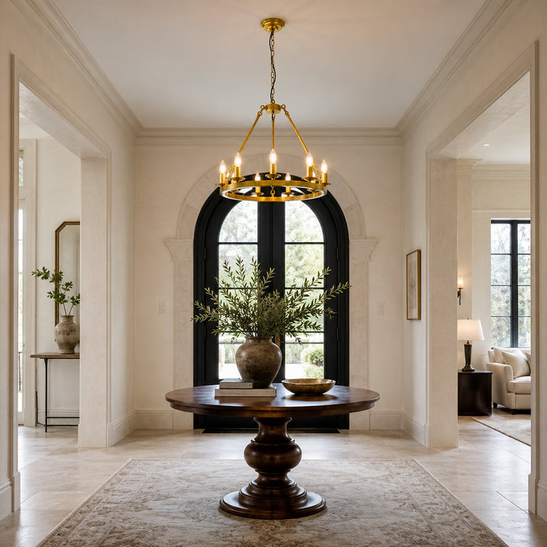 Candle ring chandelier above a dark round table in an arched entrance hall.