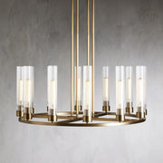 Wide brass-tone cylinder ring chandelier against a gray wall.