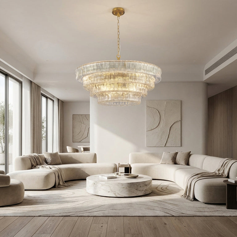 Clear round chandelier above curved sofas and a stone coffee table.