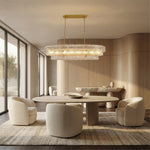 Clear glass rectangular chandelier in a curved-wood dining room.