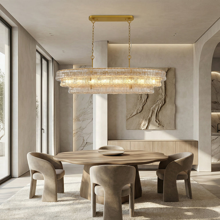 Clear glass rectangular chandelier above a table beside a stone wall.