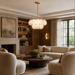 Two-tier petal glass chandelier in a living room with wood shelving and a round table.