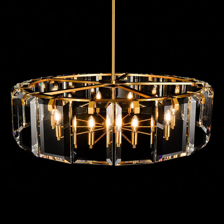 Illuminated brass-tone crystal-bar drum chandelier against a dark background.