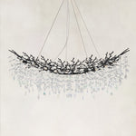 Unlit linear branch chandelier with black framework and hanging clear crystals.