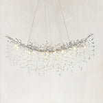Illuminated linear branch chandelier with silver-tone framework and hanging clear crystals.