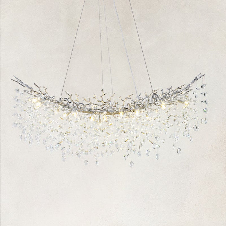 Illuminated linear branch chandelier with silver-tone framework and hanging clear crystals.
