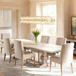Gold-tone crystal ribbon oval chandelier above a white dining table.