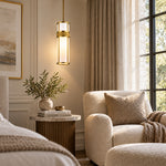 Gold-tone cylindrical pendant beside an armchair and side table.
