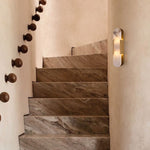 Brass oval alabaster wall sconce illuminated beside a staircase