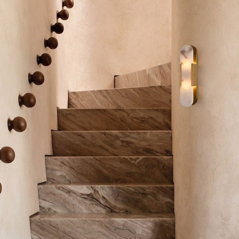Brass oval alabaster wall sconce illuminated beside a staircase