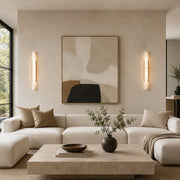 Two illuminated alabaster panel wall sconces beside artwork above a sofa