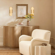 Two brass alabaster pill wall sconces beside framed art above a cabinet