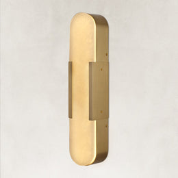 Brass alabaster pill wall sconce illuminated in an angled view