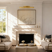 Brass picture light above framed artwork over a fireplace