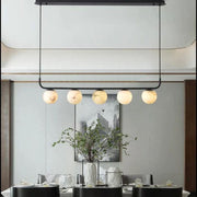 Black-framed alabaster globe chandelier hanging above a dining table.