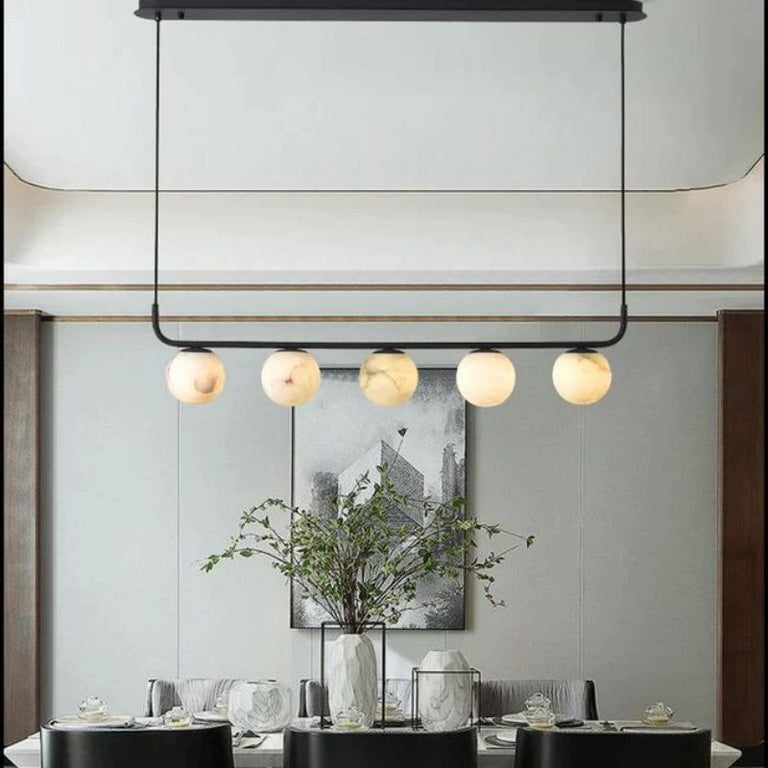 Black-framed alabaster globe chandelier hanging above a dining table.