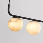 Close-up of alabaster globes attached to the black horizontal frame.