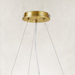 Gold-colored chandelier canopy and suspension cables.