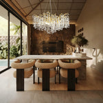 Gold-colored crystal branch chandelier above a dining table.