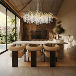 Gold-colored crystal branch chandelier above a dining table.