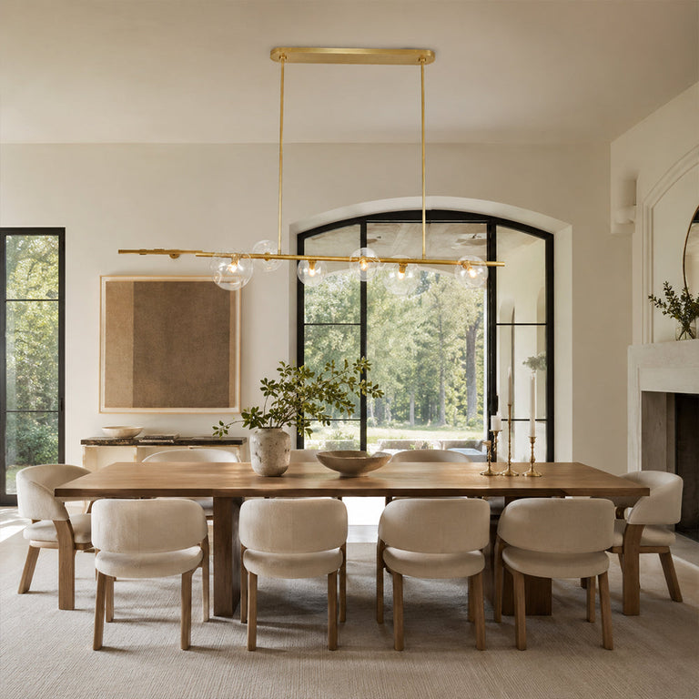 Gold-tone bubble glass chandelier above a long dining table in an interior setting