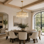 Gold-tone crystal chandelier shown in a dining room with exposed beams