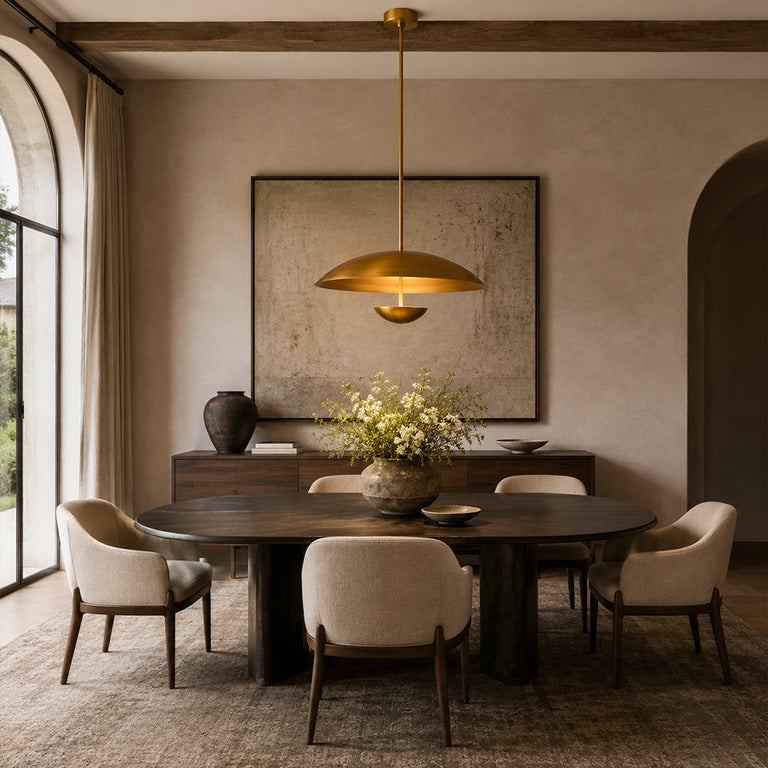 Gold-tone disc pendant above a dark dining table