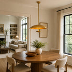 Gold-tone disc pendant above a round wooden dining table