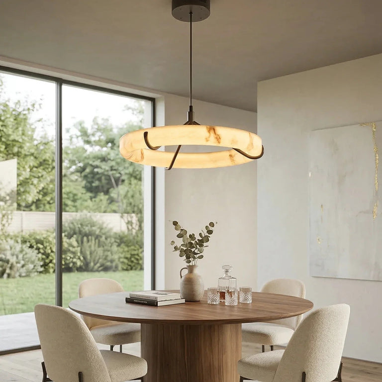 Illuminated alabaster ring pendant with black supports above a round dining table