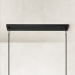 Linear glass-tube chandelier, black linear canopy and rods.