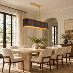 Dark linear ribbed wood chandelier above a dining table near tall windows.