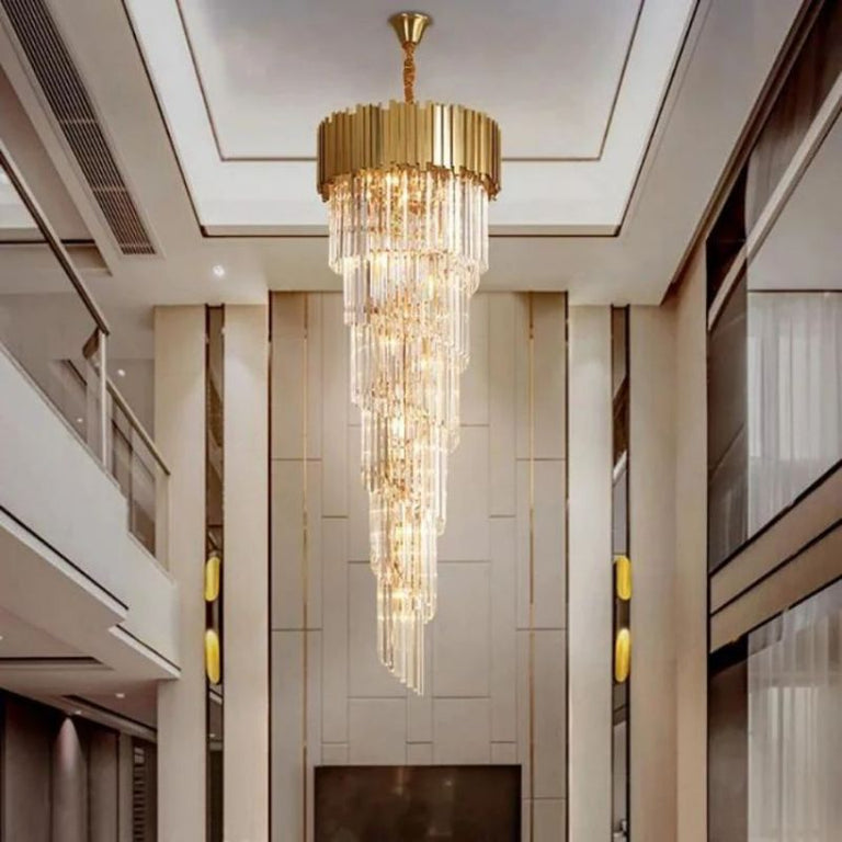 Long cascade crystal chandelier in a tall interior with an upper-level railing.