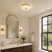 Low-profile textured glass flush mount above a vanity area