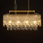 Gold-tone oval crystal chandelier, lit fixture against dark background.