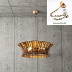 Smoke ribbed-glass drum chandelier against a concrete wall with a polished-gold finish detail