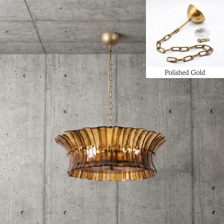 Smoke ribbed-glass drum chandelier against a concrete wall with a polished-gold finish detail