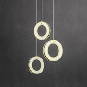 Three suspended alabaster rings with individual cables against a neutral background.