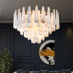 Illuminated alabaster chandelier in a furnished interior with a dark paneled wall.