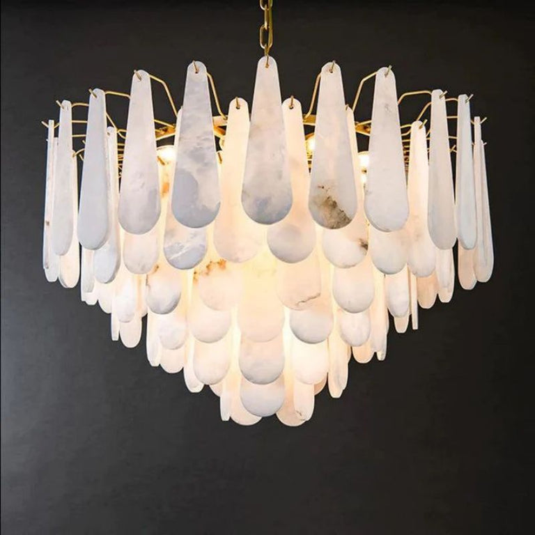 Illuminated chandelier with overlapping alabaster teardrop panels against a neutral background.