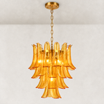 Illuminated tiered amber chandelier with curved panels and gold-tone chain suspension.