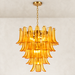 Illuminated tiered amber chandelier with curved panels and a gold-tone canopy.