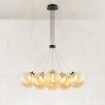 Illuminated glass globe chandelier with a black canopy and fanned suspension wires.