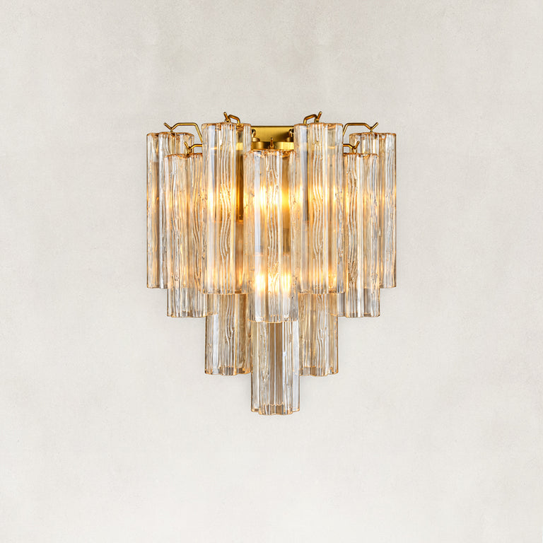 Illuminated wall sconce with tiered clear glass tubes and gold-tone hardware.