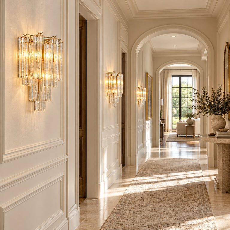 Tiered glass wall sconces with gold-tone hardware along a light-colored hallway.